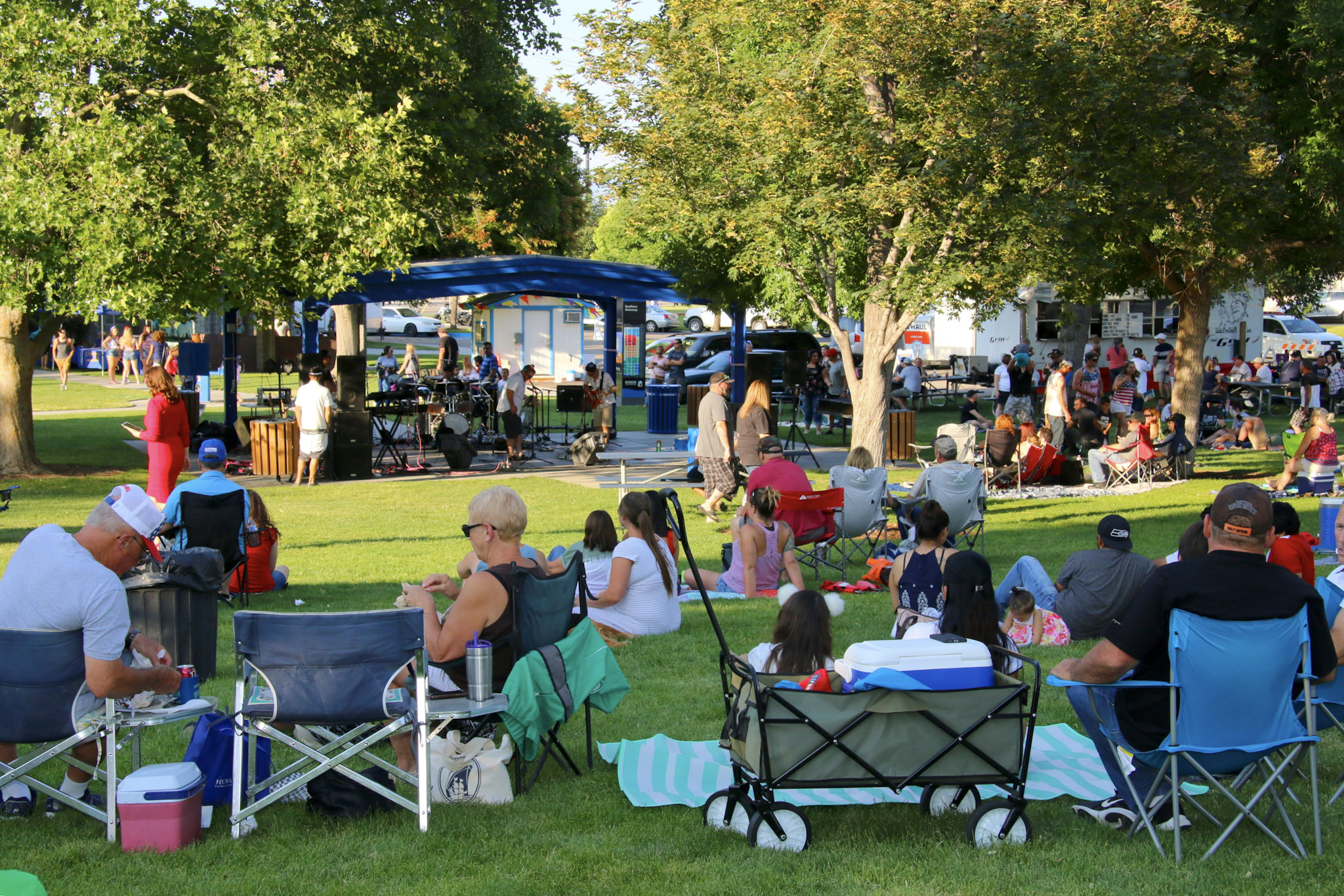 Residents in lawn chairs and on blankets enjoying live music in Storey Park